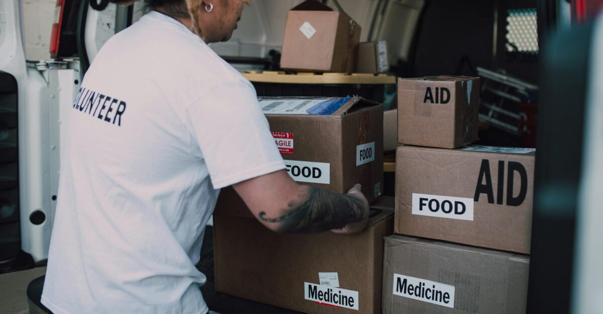 A volunteer organizes aid boxes containing food and medicine in a van for community service