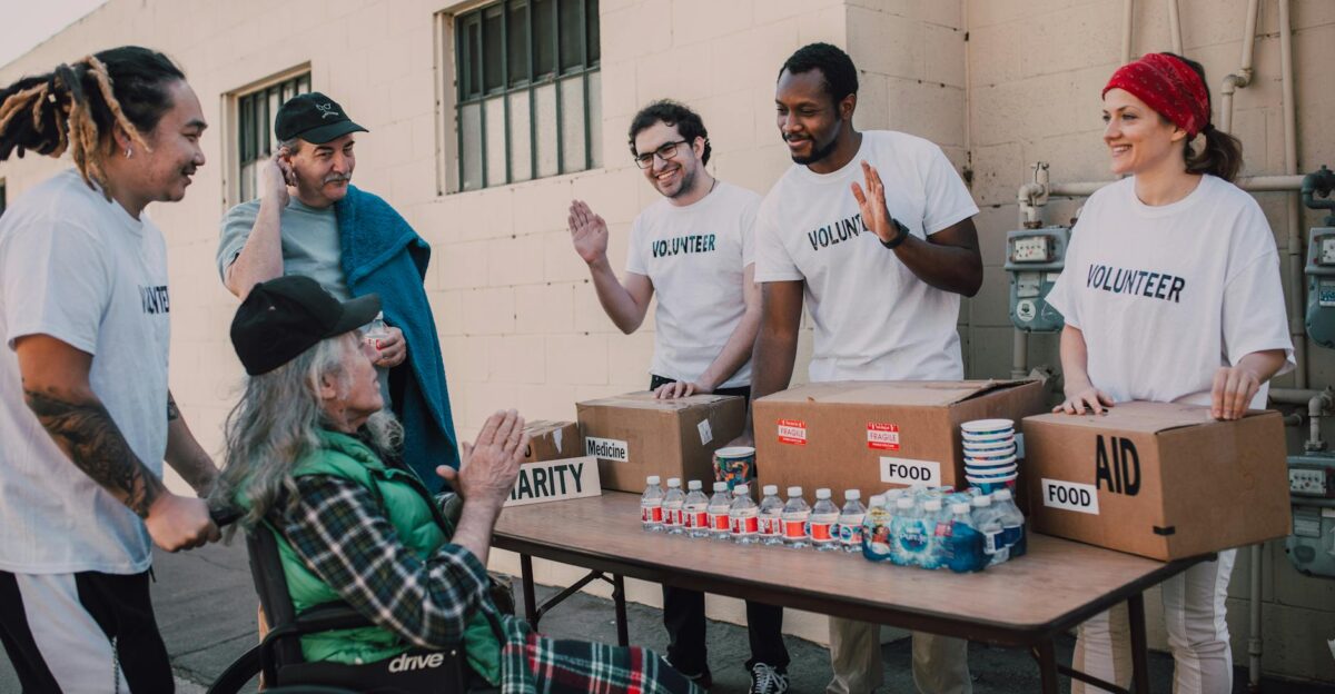 Group of volunteers providing food and aid to a person in wheelchair outdoors