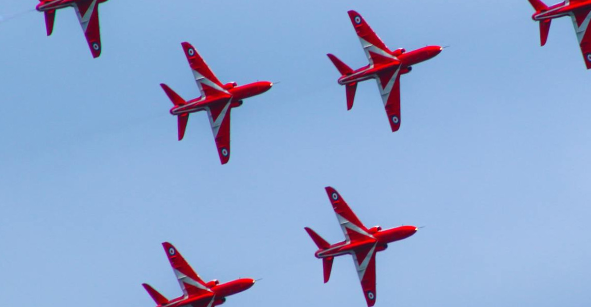 Red Arrows formation flying against a blue sky showcasing aerobatic precision