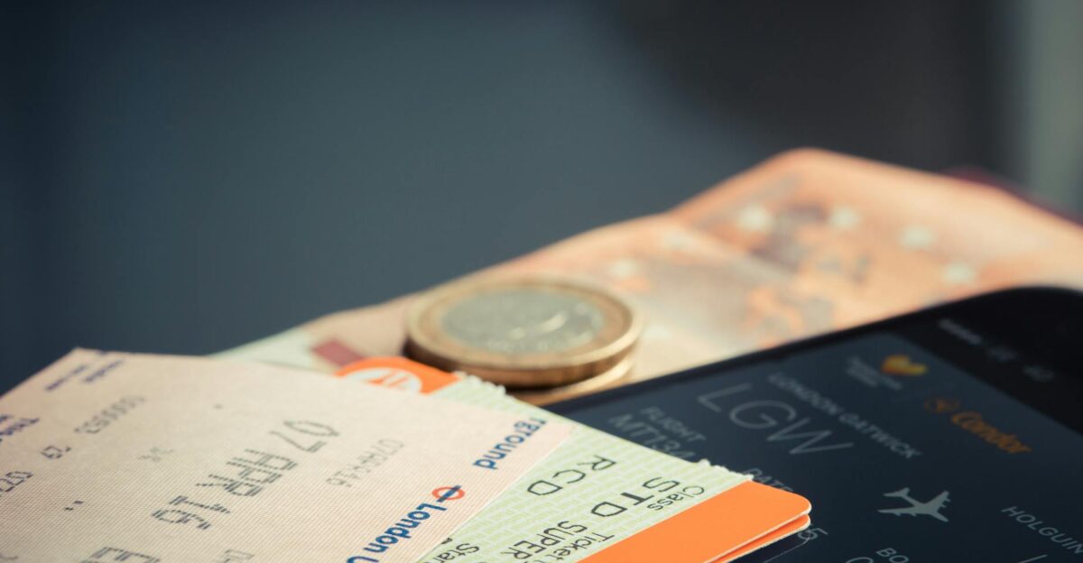 Airline ticket with euro coins and smartphone displaying flight details