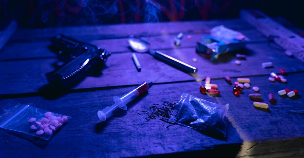 A moody scene displaying drugs a gun and smoke under dramatic lighting