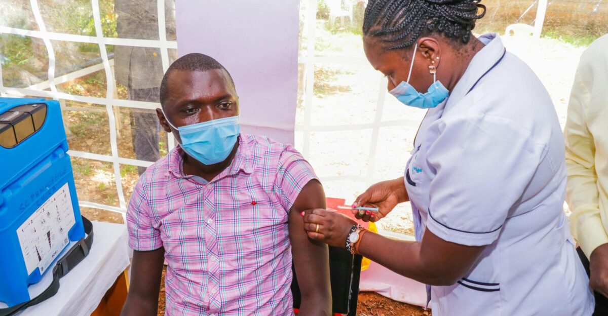 A nurse gives a COVID-19 vaccination to a man at an outdoor health facility
