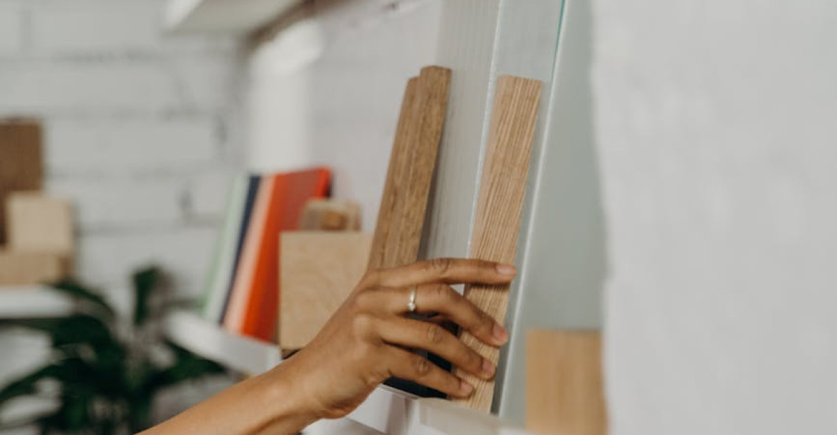 Close-up of a hand selecting wooden samples from a shelf in a carpentry store