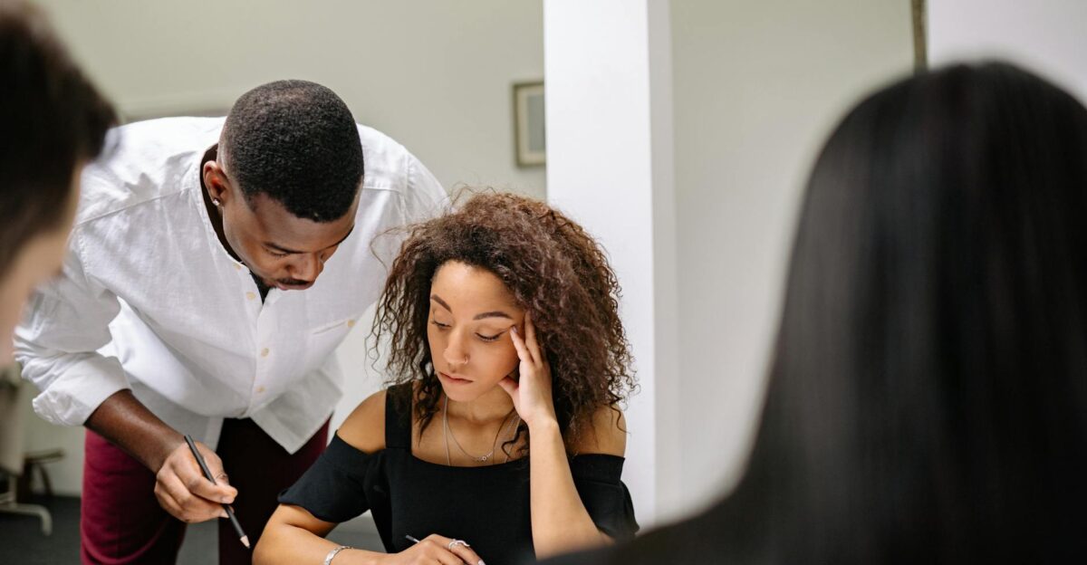 Businesswoman feeling stressed during a team meeting as colleagues assist