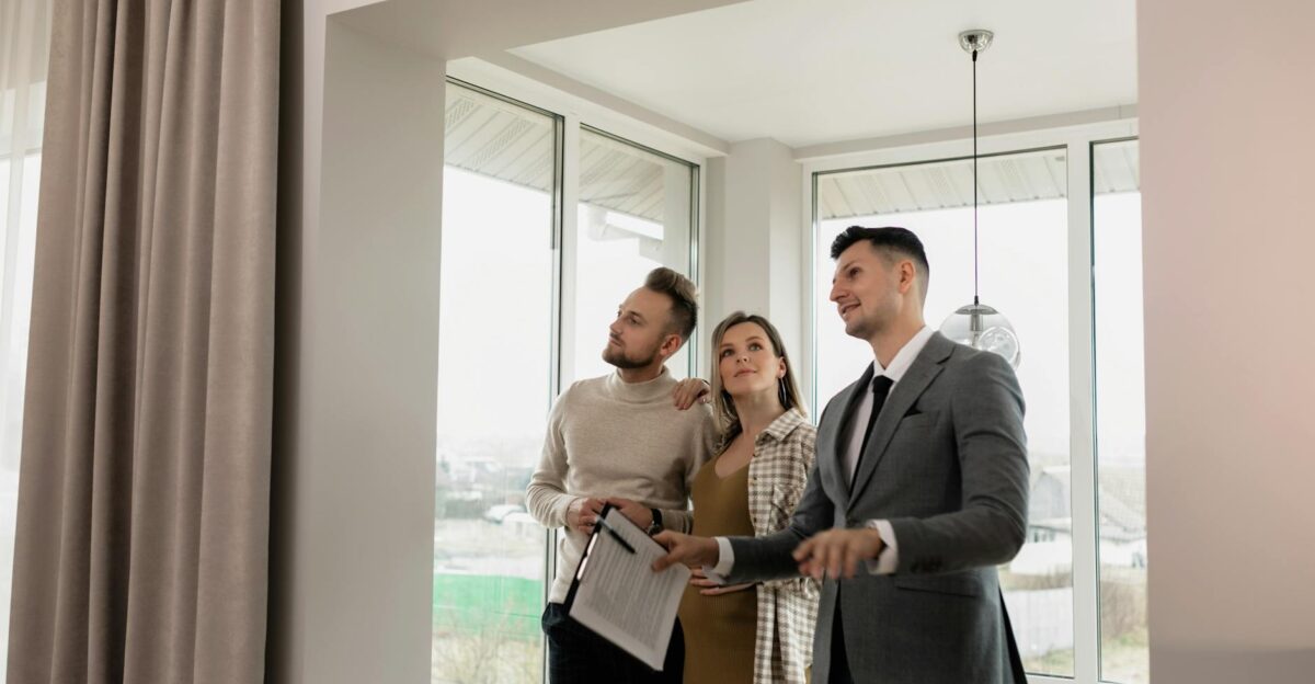 A real estate agent showing a modern home to a young couple during a daytime viewing
