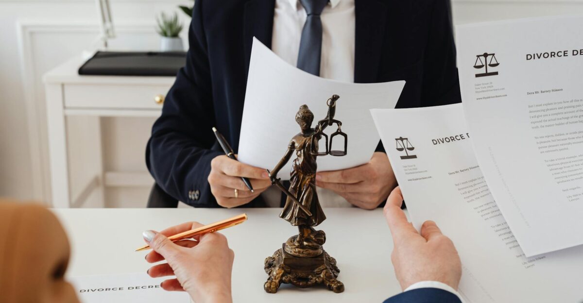 Legal professionals reviewing divorce documents in a law office with a Lady Justice statue