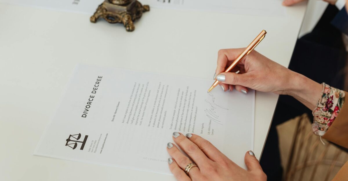 Close-up of hands signing a divorce decree document on a desk showcasing legal process