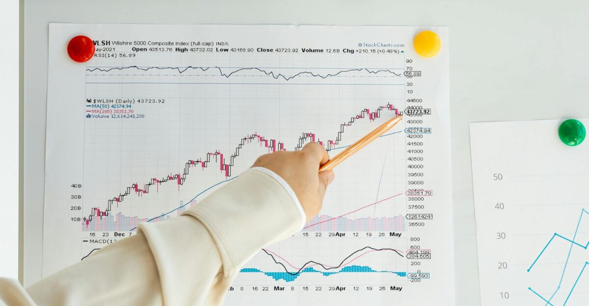 Close-up of a woman s hand pointing to data trends on a stock market chart using a pencil