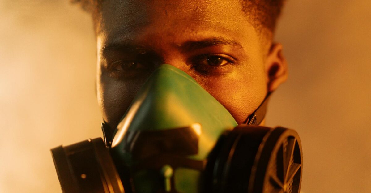 A man wearing a respirator mask against a smoky or polluted background