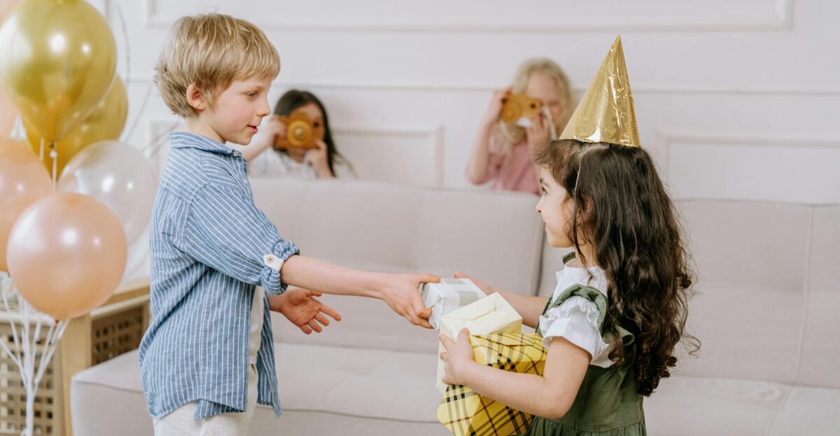 Children celebrating indoors with gifts balloons and party hats for a joyful birthday gathering