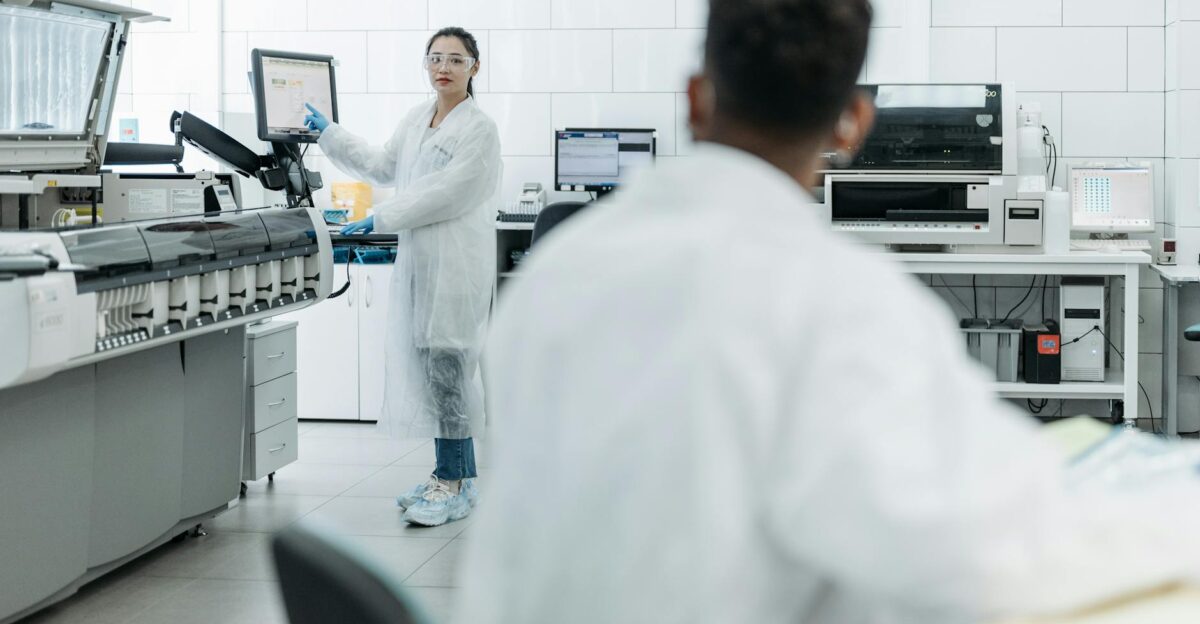 Scientists in a lab environment using monitors and wearing safety gear
