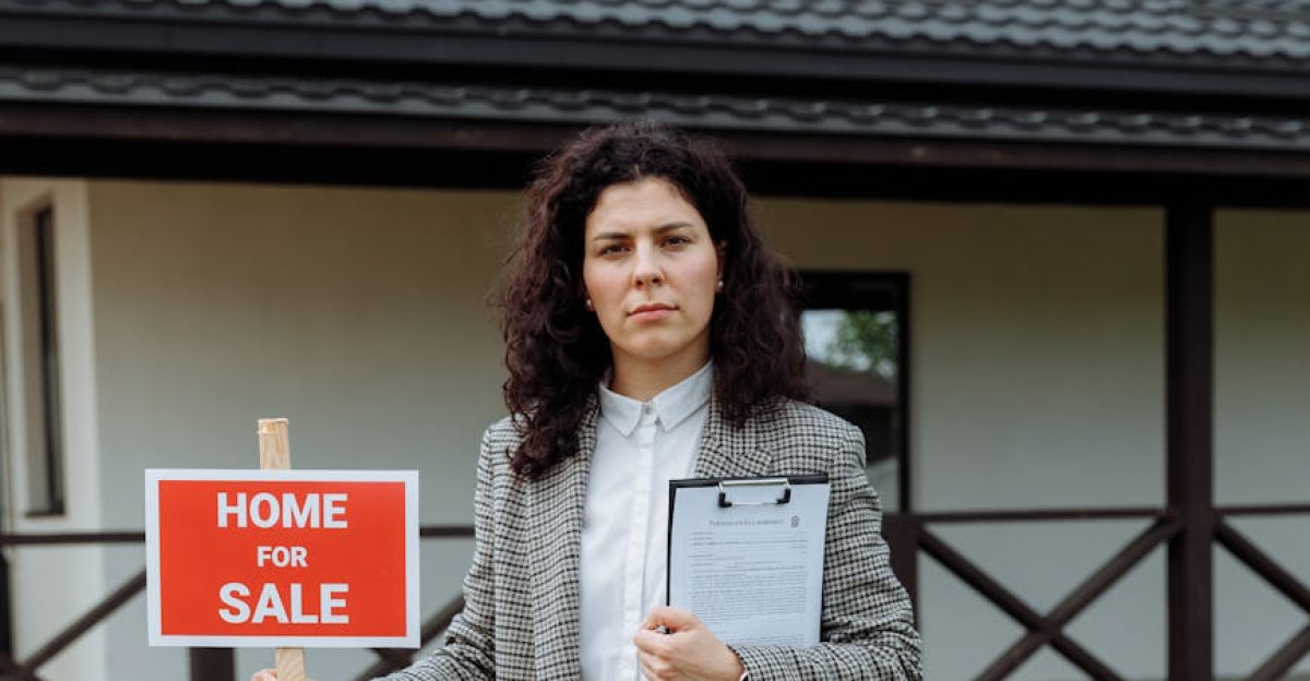 Female real estate agent outside house for sale holding sign