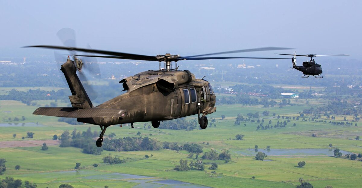 Aerial view of military helicopters flying over a green landscape on a clear day