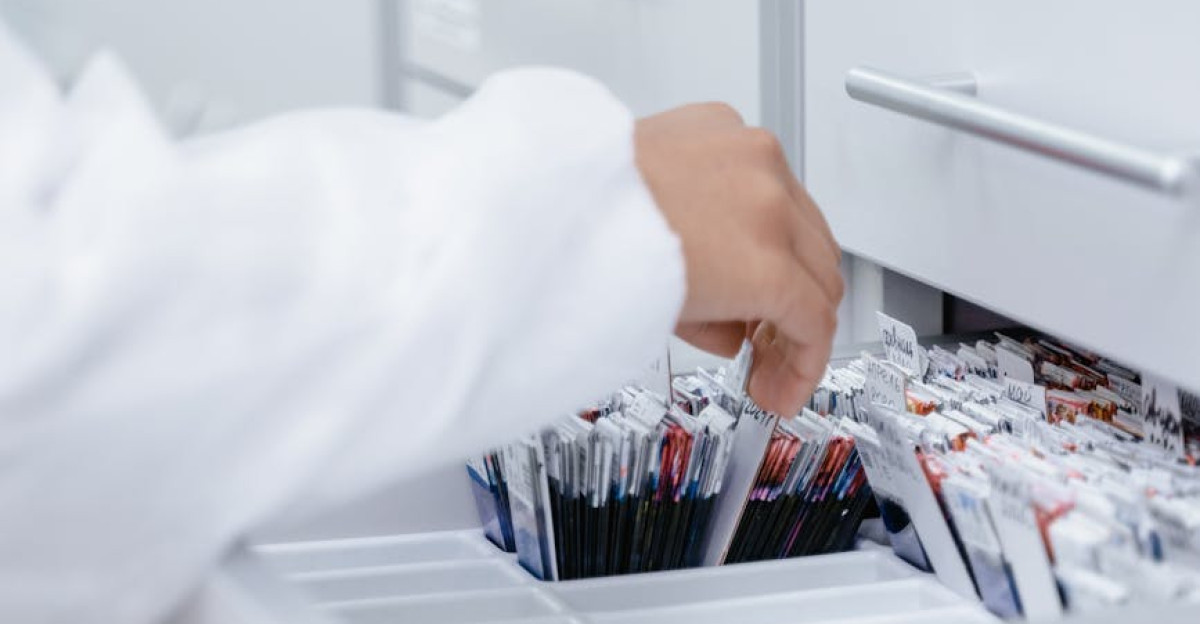 A person wearing a lab coat organizing files in a medical laboratory drawer