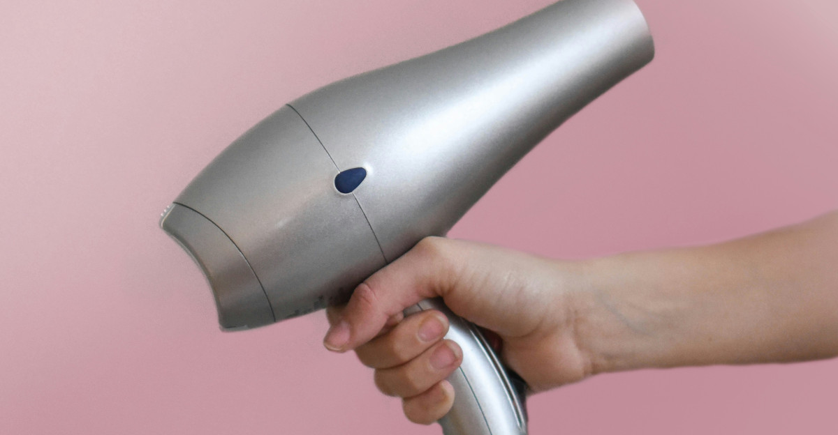 person holding gray corded hair dryer
