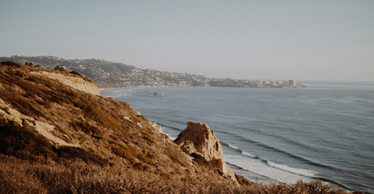 mountain beside sea under white sky