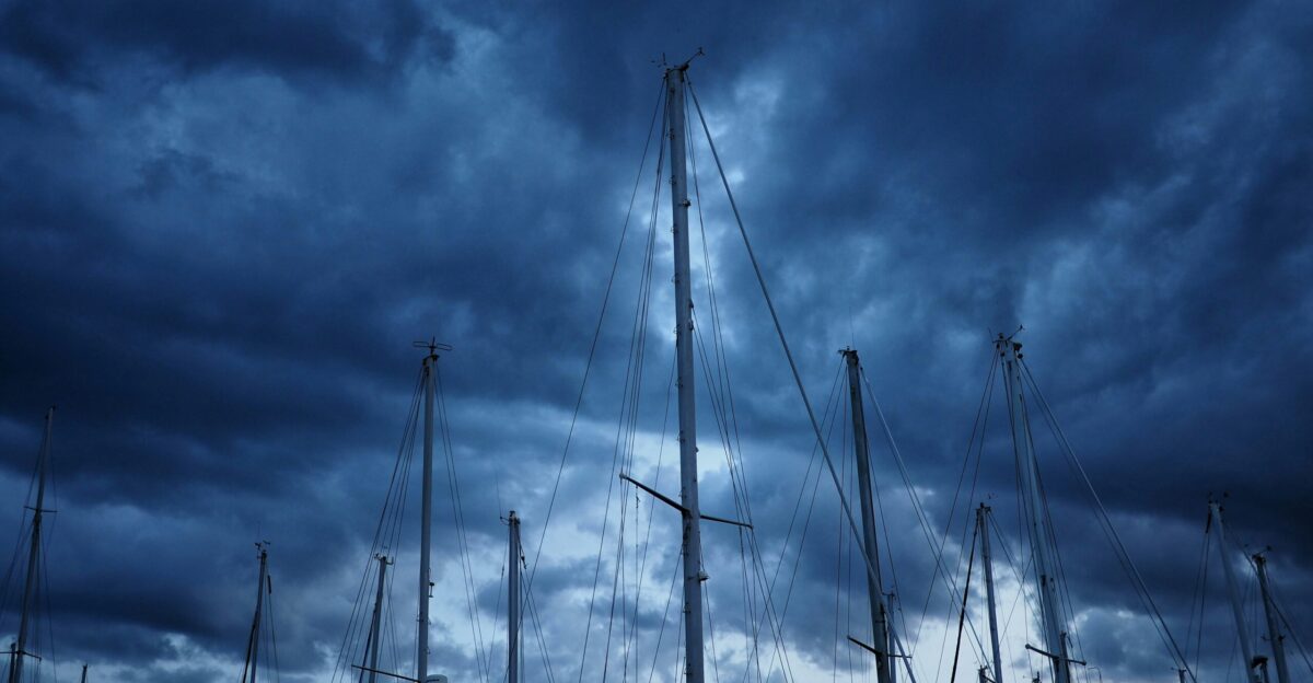 white sail boat on sea under cloudy sky during daytime