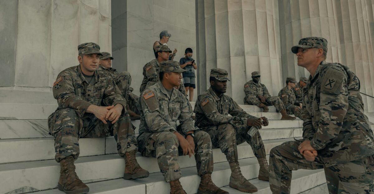 men in camouflage uniform standing near white wall