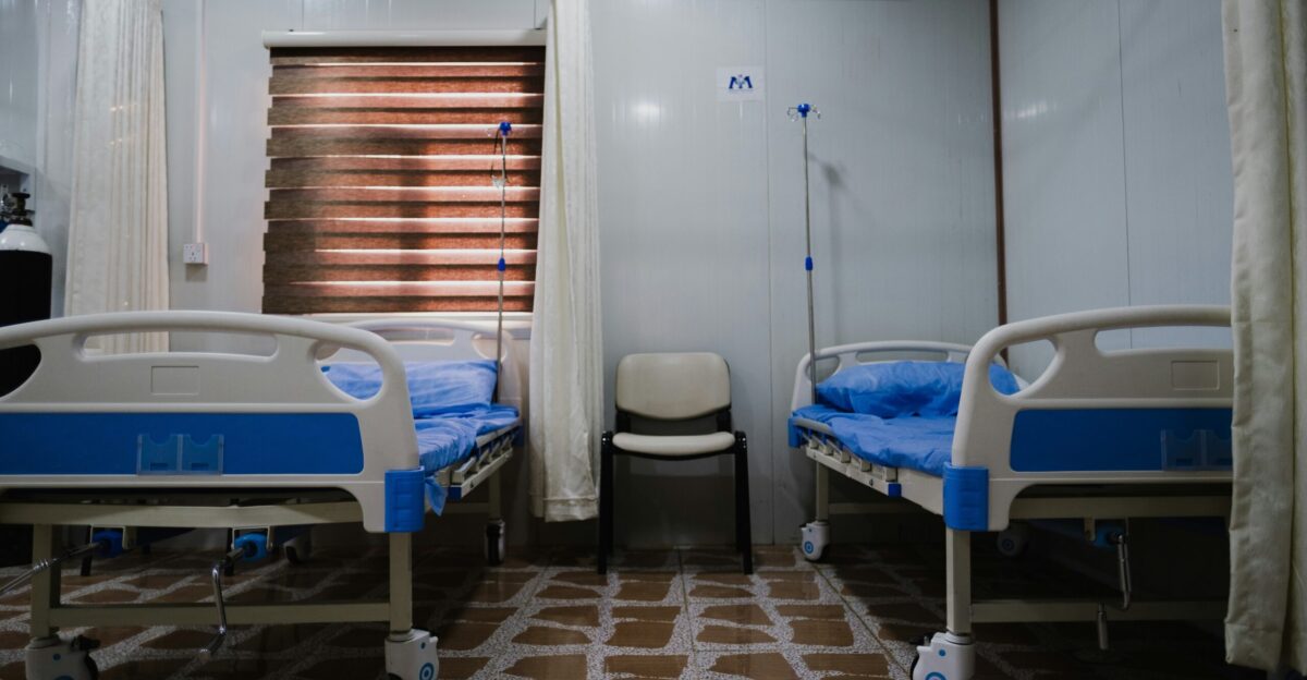 white split type air conditioner over white and blue hospital bed