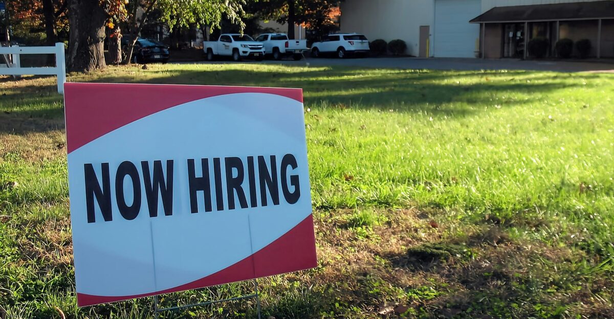 a now hiring sign in front of a building