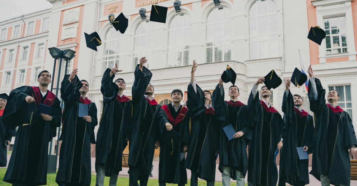 a group of people in graduation gowns holding their caps up