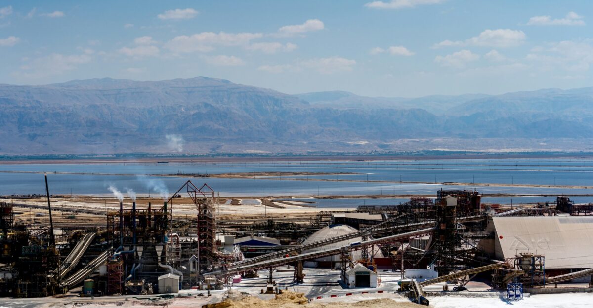 a large factory with a body of water in the background