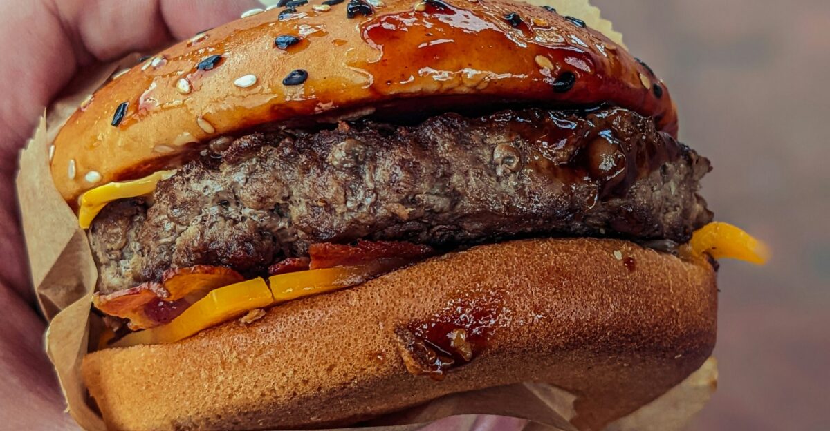 a person holding a hamburger in their hand