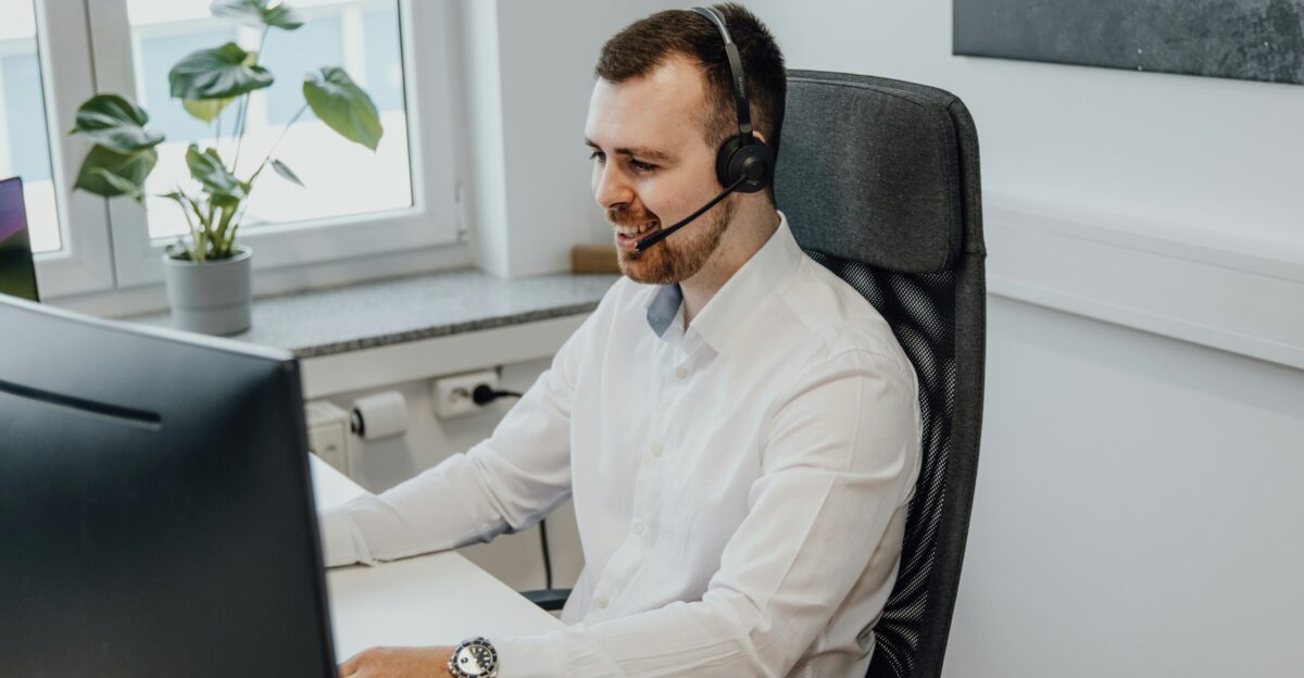 a man wearing a headset sitting in front of a computer