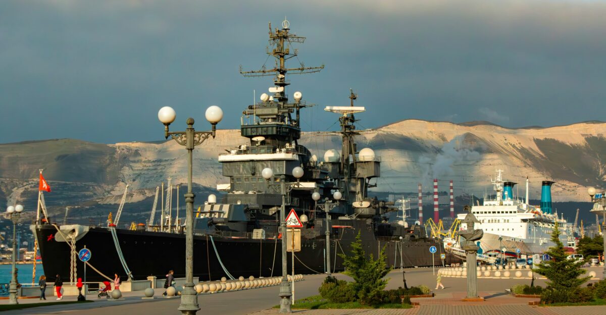A large ship docked in a harbor with mountains in the background
