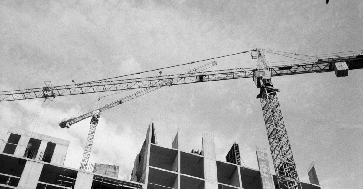 A black and white photo of a crane in front of a building