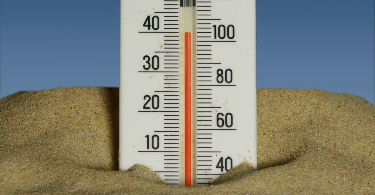 A thermometer in the sand with a blue sky in the background
