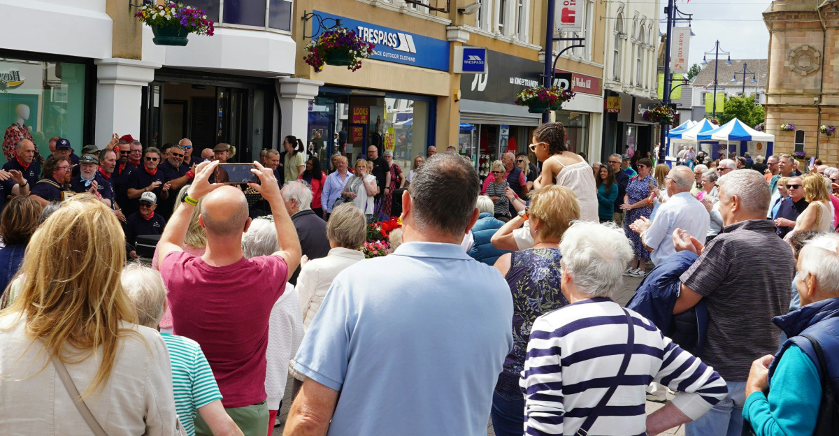 A crowd watches an event in a town square