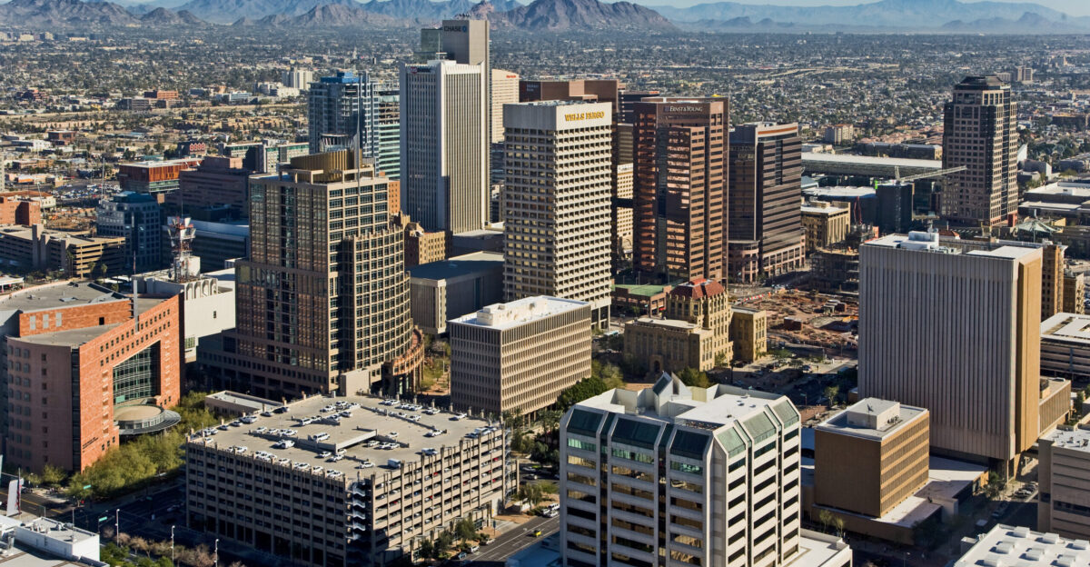 Skyline view of Phoenix - looking northeast from a helicopter from above the 4th Avenue Jail Foreground is the Central City Village and Central Avenue Corridor of Downtown Phoenix In the foreground Municipal and County Courts are visible along with other Downtown skyscrapers in the background Camelback Mountain and Four Peaks are visible