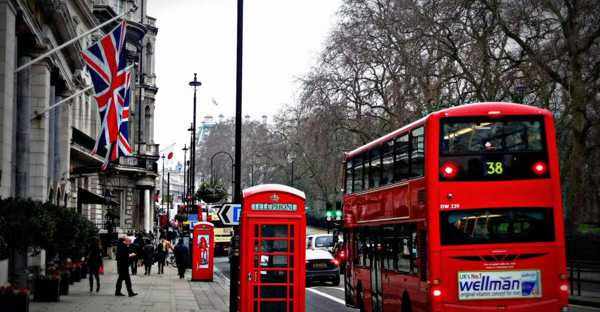 Classic London scene featuring a red double-decker bus and iconic phone booth on a busy city street