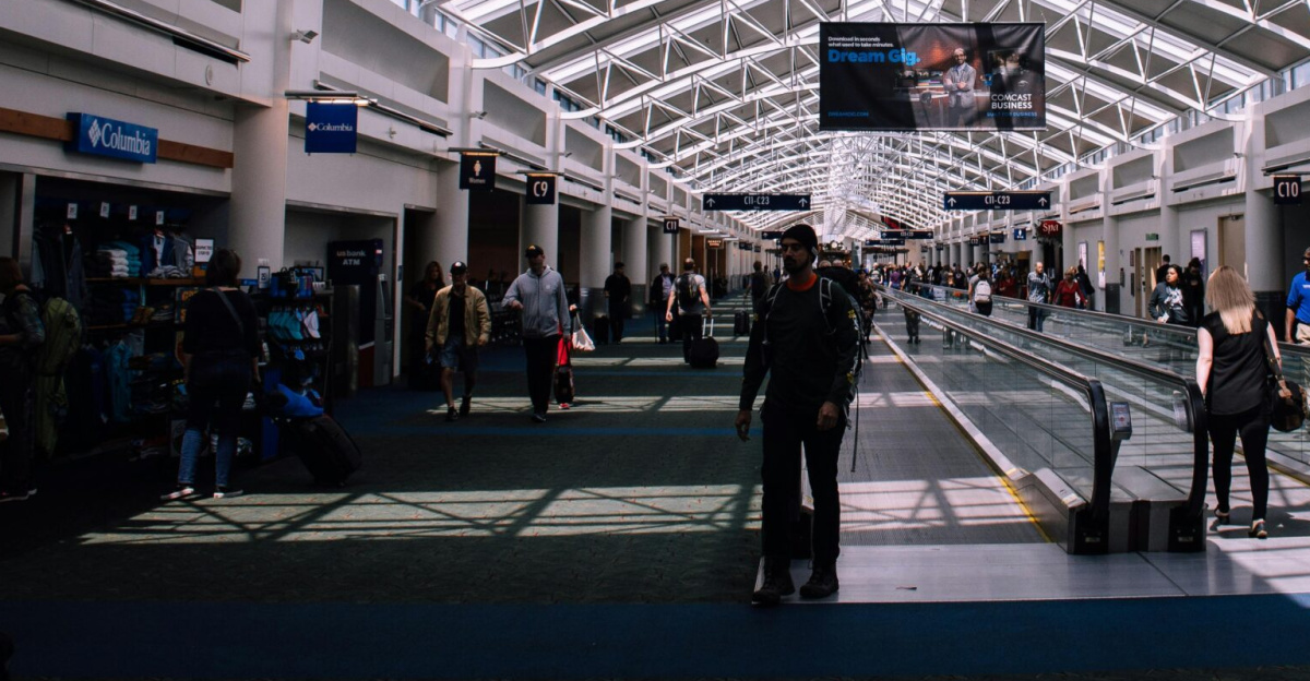 Spacious airport terminal with moving walkway and travelers, showcasing modern architecture.