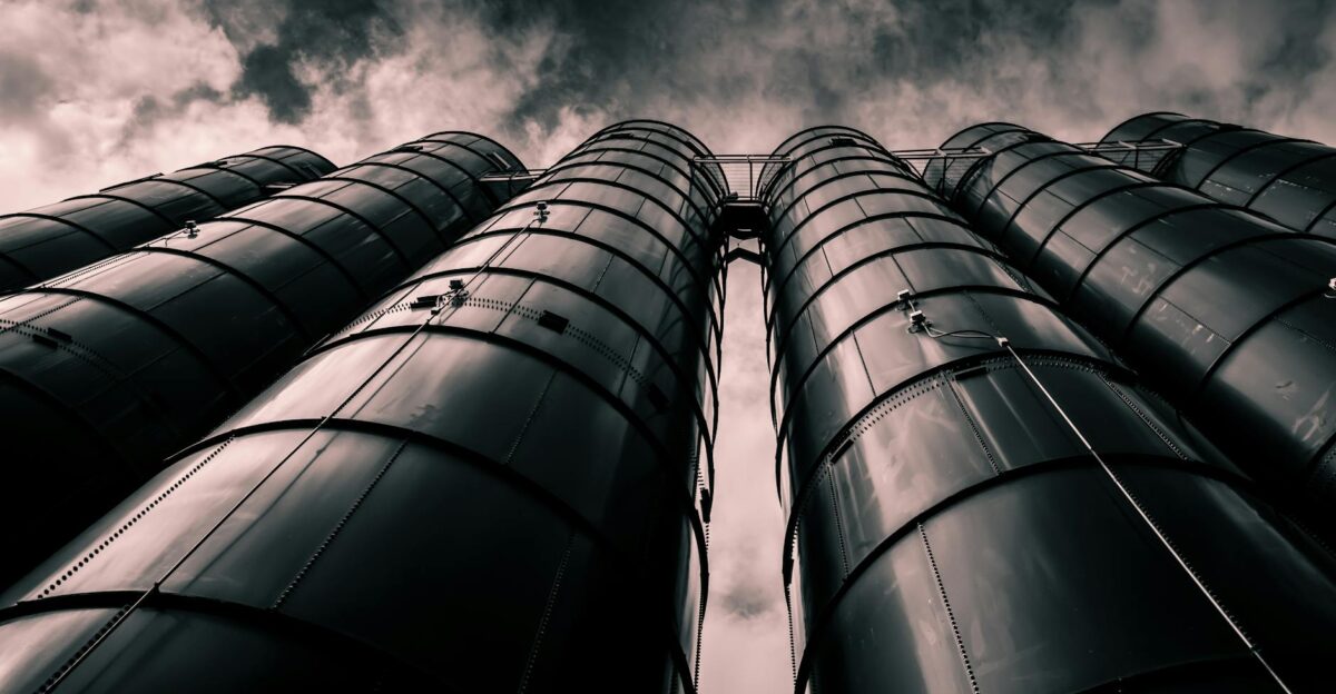 Low angle view of industrial silos with a dramatic cloudy sky in the background emphasizing modern industry