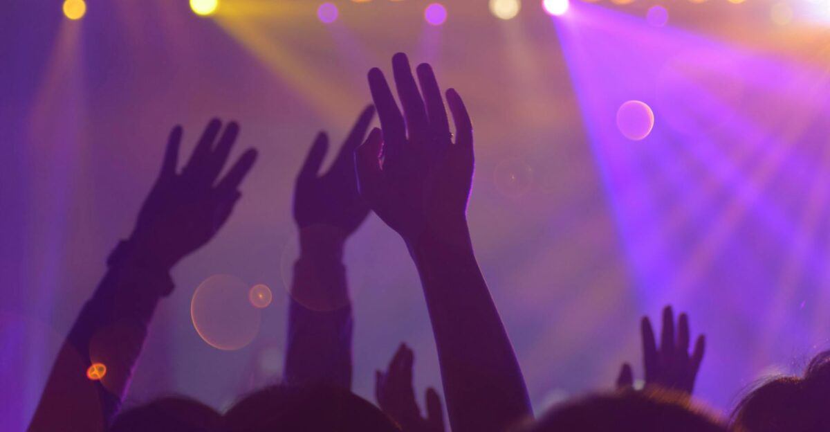 Silhouettes of a lively audience with raised hands at an energetic nightclub event