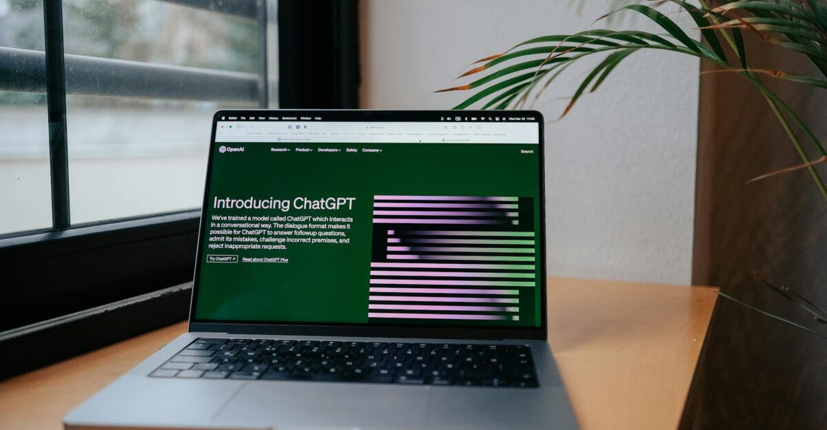 A laptop displaying ChatGPT on a desk by a window featuring a modern home office setup