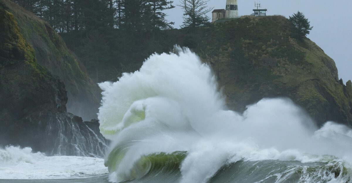 Powerful waves crash against cliffs beneath a lighthouse showcasing nature s raw energy by the sea