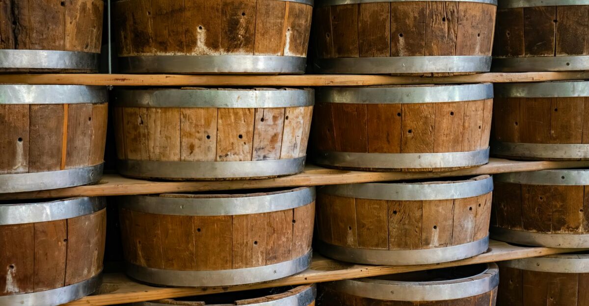Close-up view of wooden barrels stacked on shelves inside a winery storage area