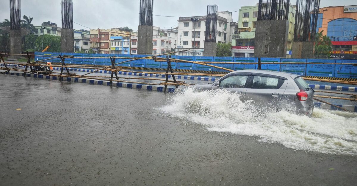 A car navigates a flooded street in Kolkata India after heavy rain showcasing urban challenges