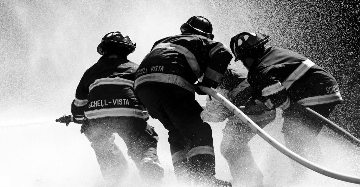 Firefighters in full gear battle heavy water spray in an intense operation