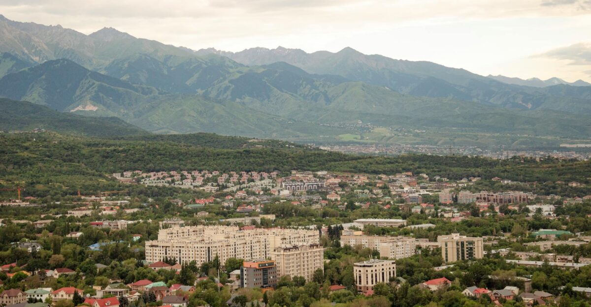 A panoramic view of Almaty city with lush greenery and mountains in the background