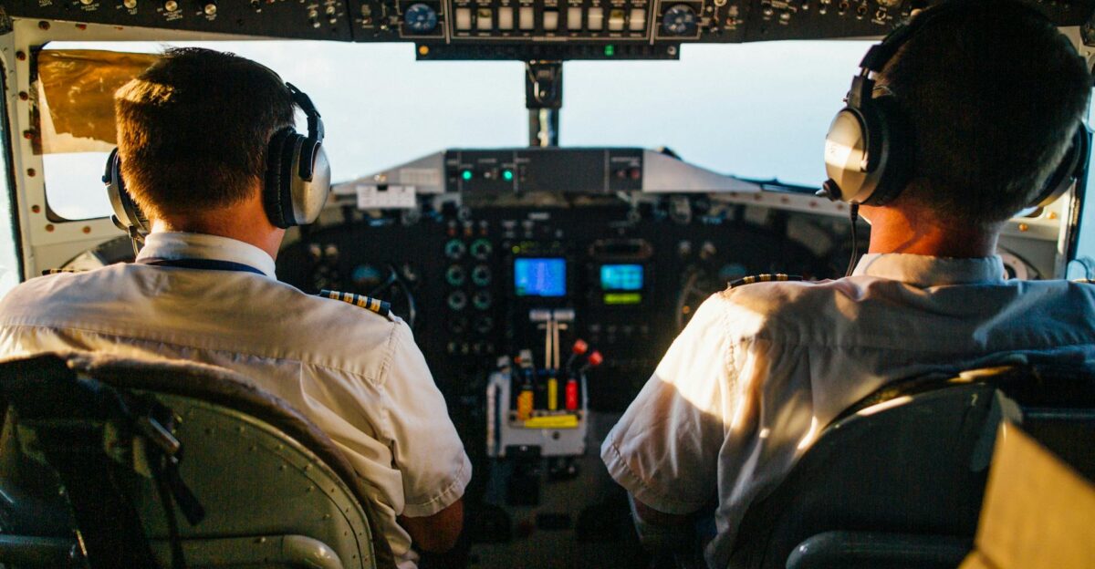 Two pilots in cockpit navigating airplane at high altitude daylight