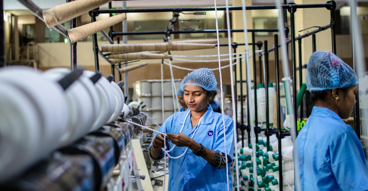 Female workers operating machinery in a textile factory India