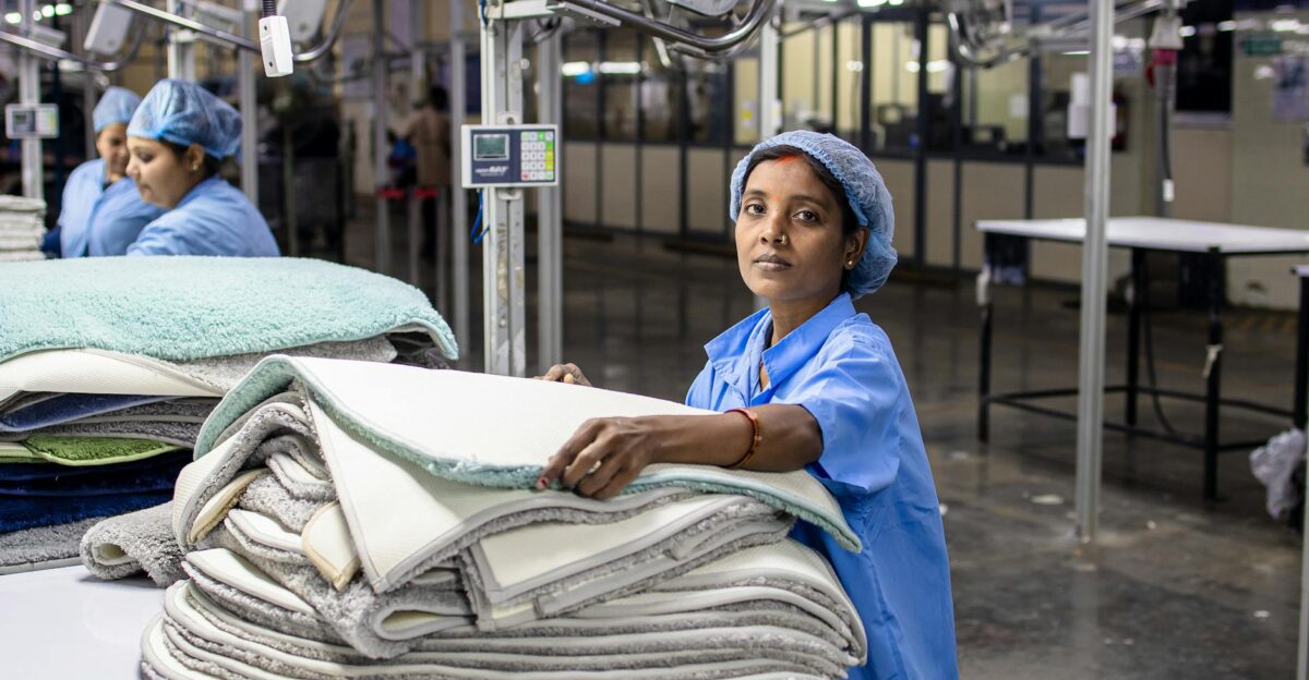 Woman in blue uniform handling textiles in a modern industrial factory