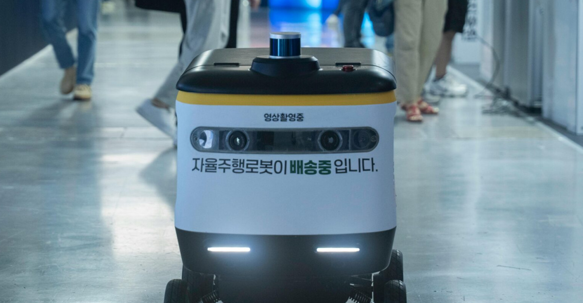 Autonomous delivery robot navigating indoors during a technology event.