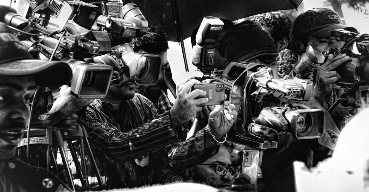 A group of photographers in Dhaka capturing an event with cameras and umbrellas
