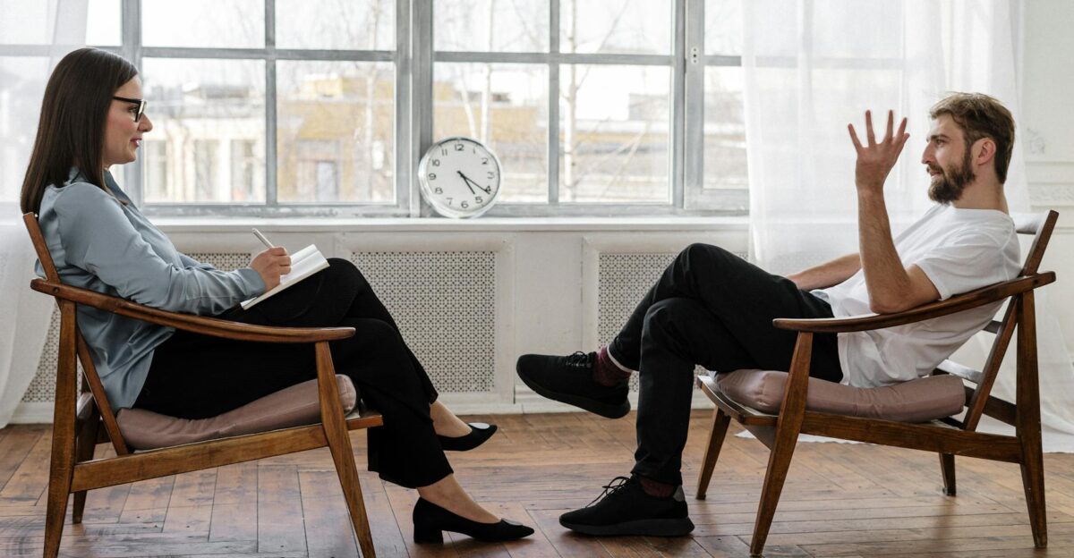 A therapist engaging in a counseling session with a male patient to support mental health
