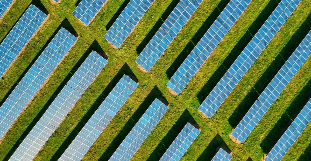 High-angle aerial shot of solar panels in a lush green field located in Rockbeare UK
